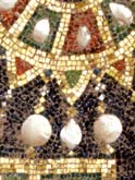 Detail of  jewel-studded gold necklace with dangling pearls.